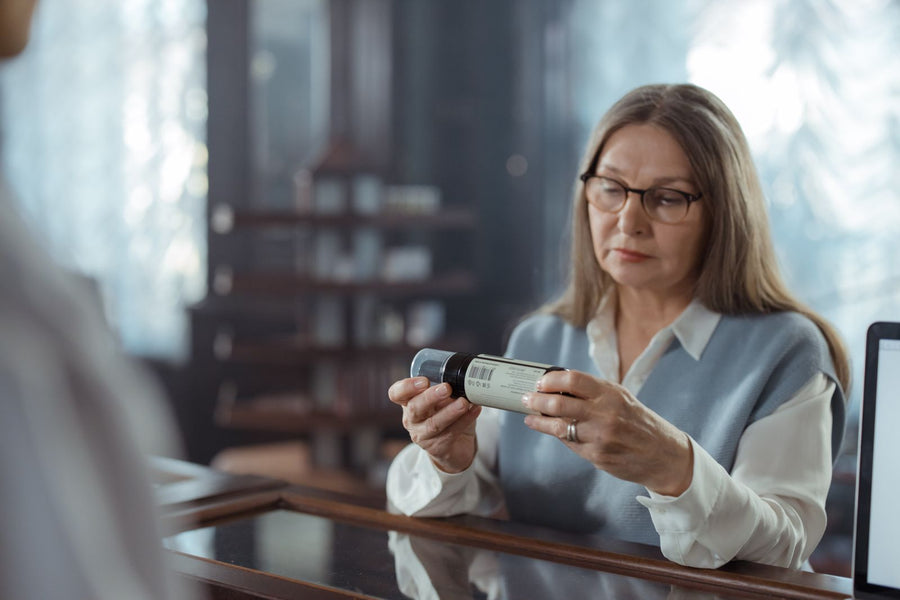 Mujer leyendo con atención la etiqueta de un frasco antes de elegir un suplemento